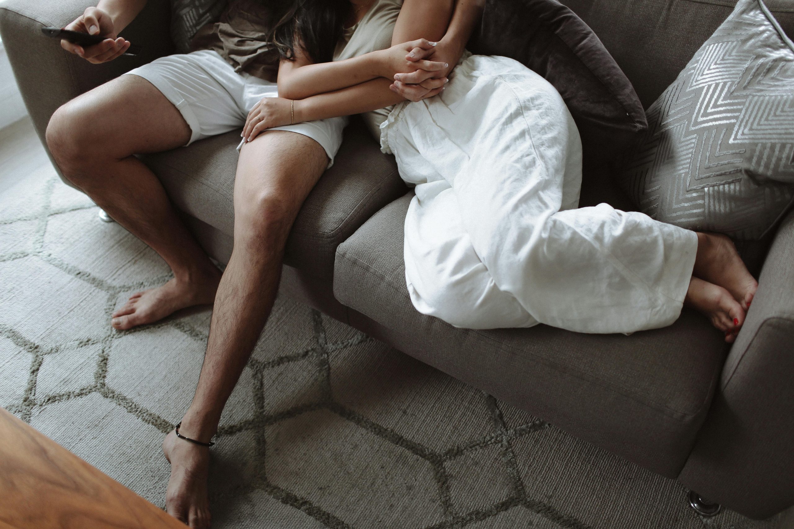 Couple lounging on a sofa at home, showing affection and relaxation together.